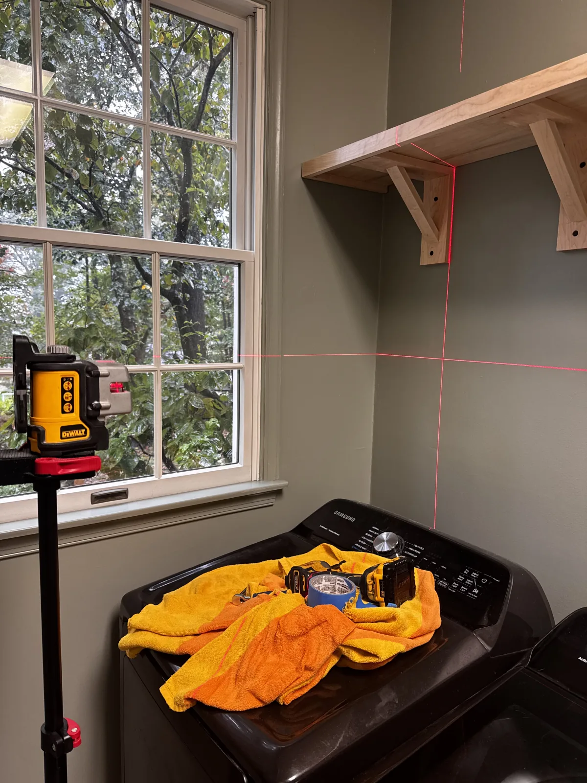 Custom laundry shelf installation aligned with a laser level