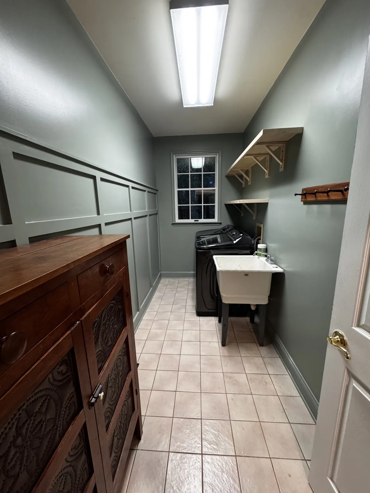 Finished laundry room with painted panel molding and custom utility shelves