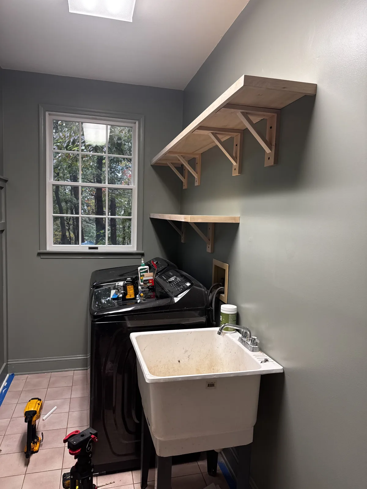 Custom wood utility shelves and handmade brackets installed above a washer