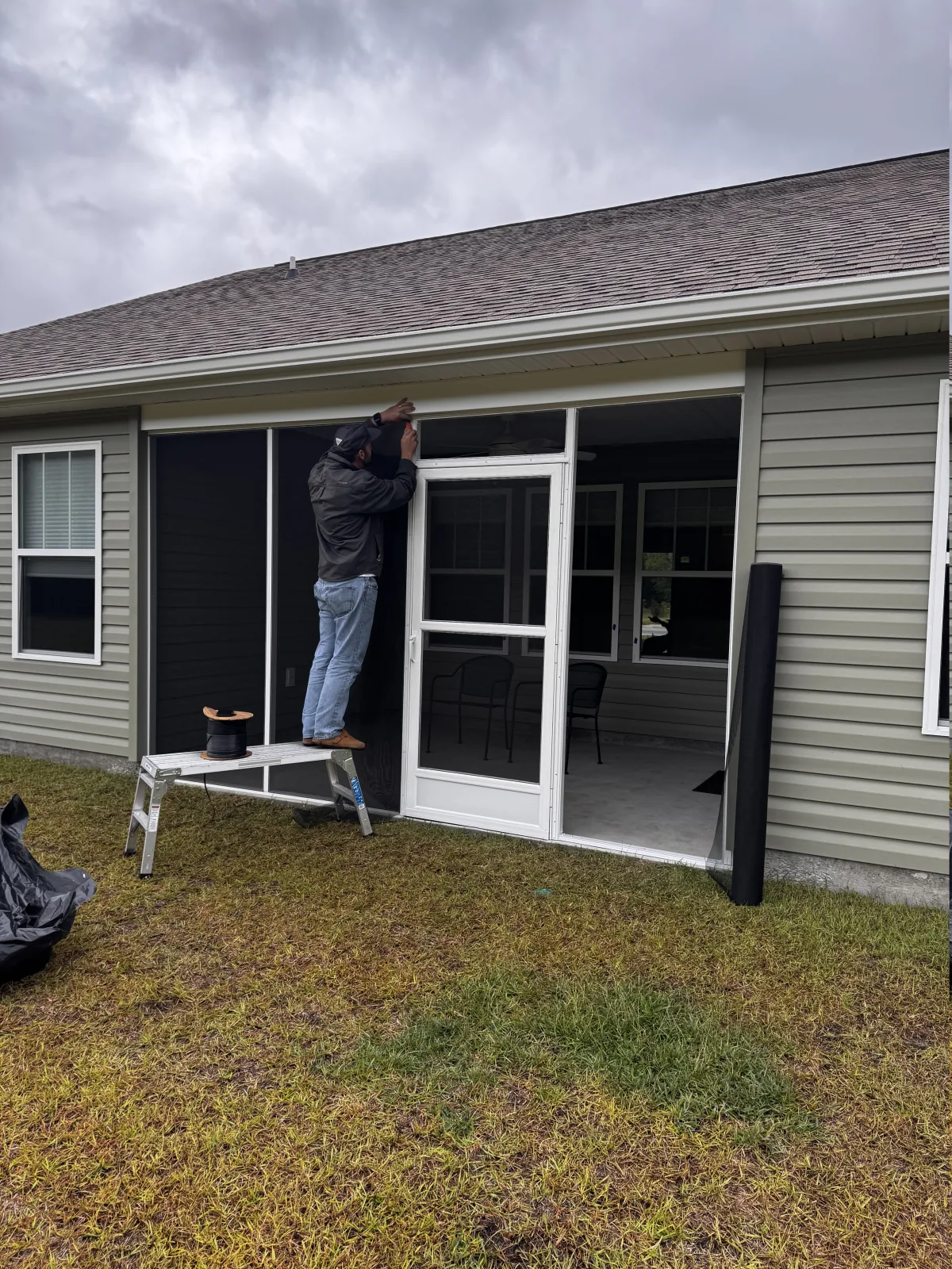 Screen mesh being installed across a framed covered porch